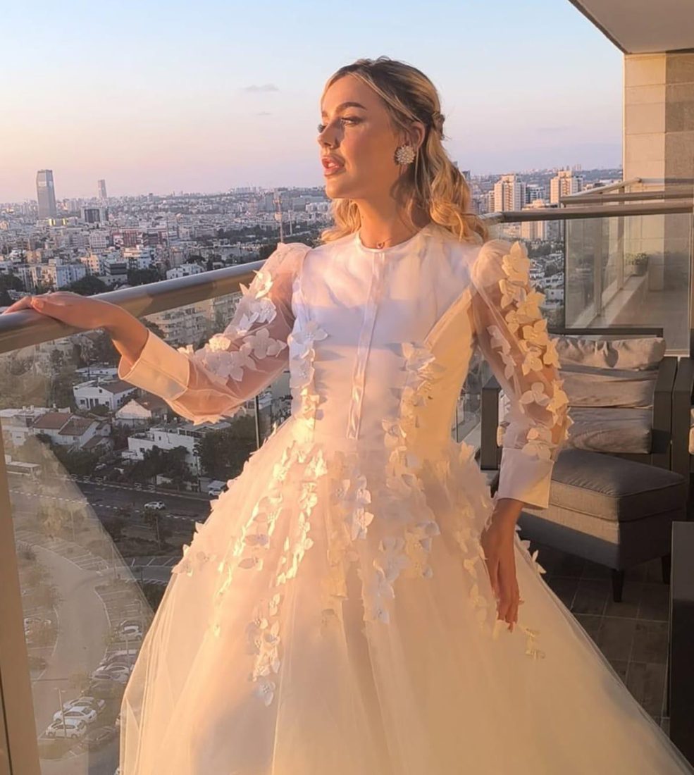 כלה בשמלת טול עם פרחים תלת־ממדיים, במרפסת בשקיעה