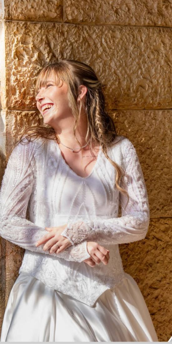 כלה צוחקת ליד קיר אבן